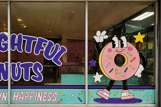 Window display of Delightful Donuts with cartoon donut character and colorful text.