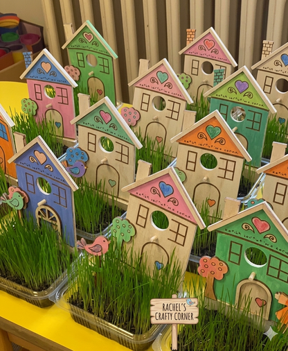 Colorful wooden houses with plants on a table, labeled 'Rachel's Crafty Corner'.