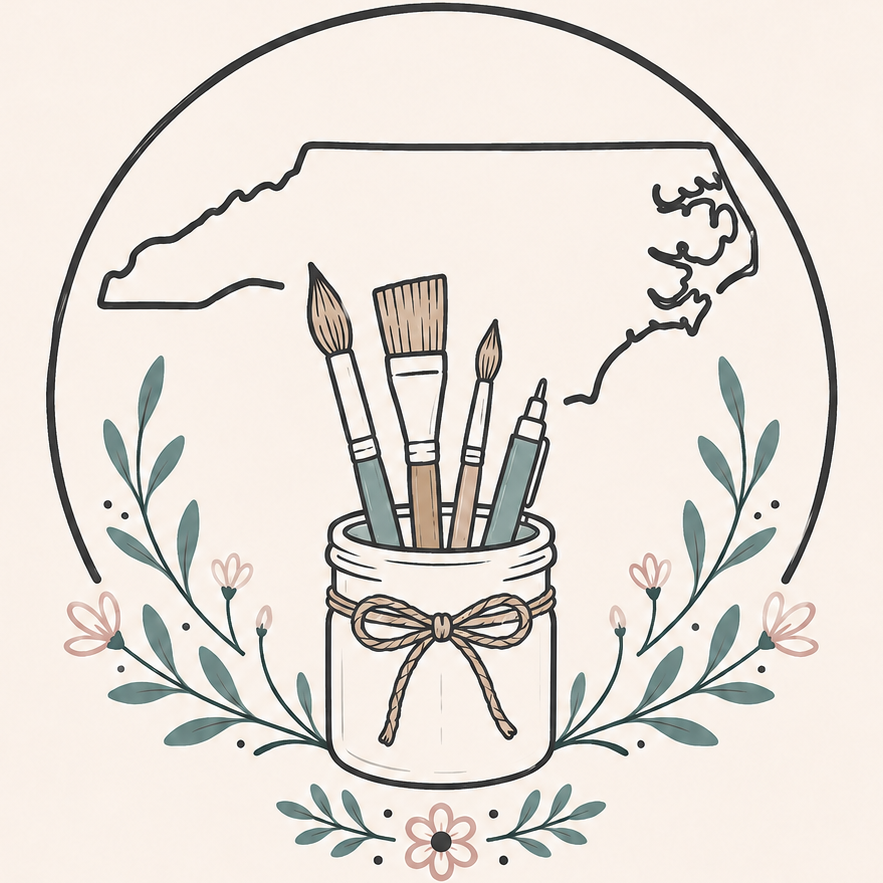 A circular graphic illustration featuring paintbrushes and a pencil in a jar with a bow, surrounded by delicate floral leaves and a black outline of North Carolina on a light cream background.