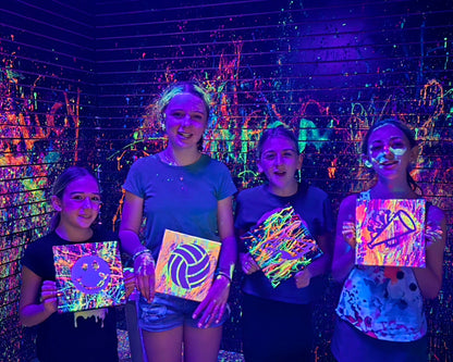 A person sitting in front of a colorful splatter paint art